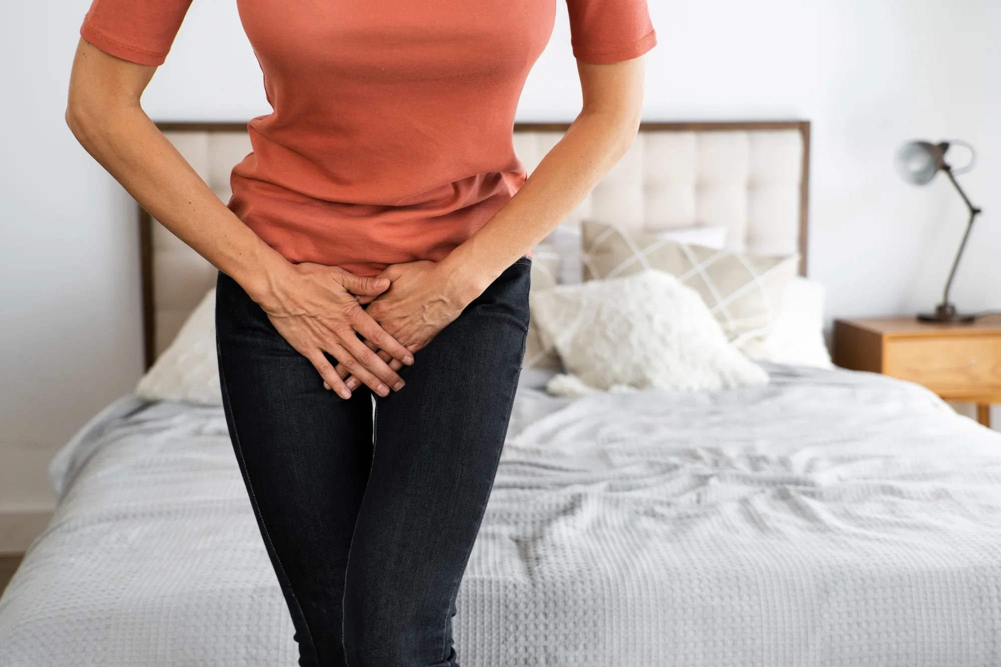 Mujer sentada con expresión incómoda, cruzando las piernas discretamente.